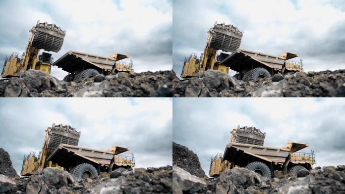 一辆大型黄色自卸车驶上，满载着矿石，泥土。石头后面的底视图。4K