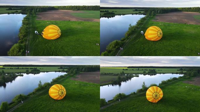 家庭监督在河岸上飞行的大型黄色气球的准备工作