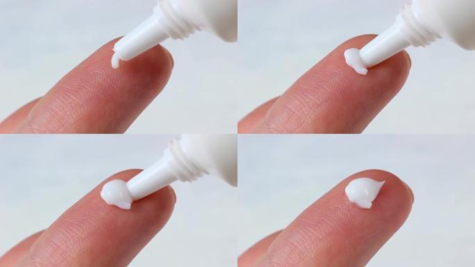 白色保湿霜涂抹在女性手指上，背景浅
