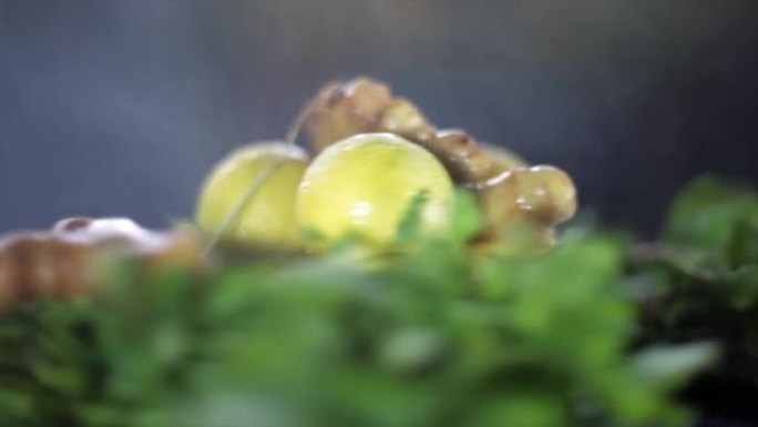 在黑色闪亮的木质表面上拍摄了新鲜柠檬，姜香菜和一些薄荷叶的电影特写镜头。柳条篮子里的新鲜绿色蔬菜。