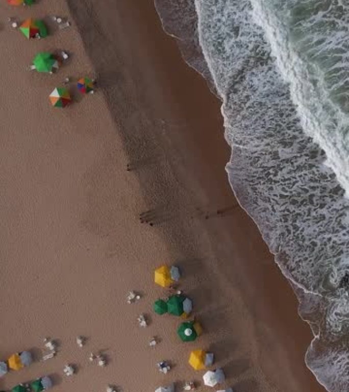 海浪在日光浴浴床的沙滩上飞溅的鸟瞰图