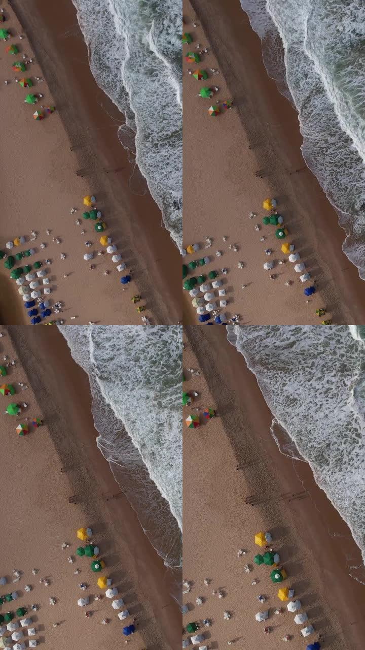 海浪在日光浴浴床的沙滩上飞溅的鸟瞰图