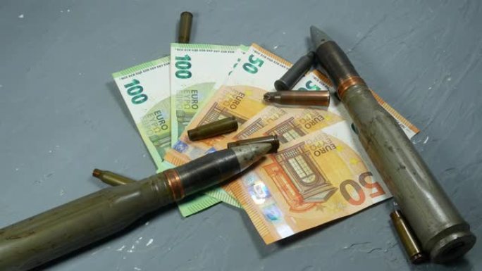 灰色背景上有欧元钱、子弹、炮弹、子弹和弹丸。租借法案和军队的概念。贩卖武器弹药。军事工业，战争，全球