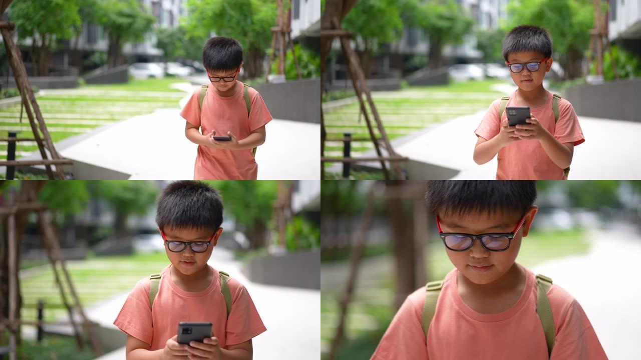 亚洲男孩走路时使用智能手机上网，在日常生活中玩游戏
