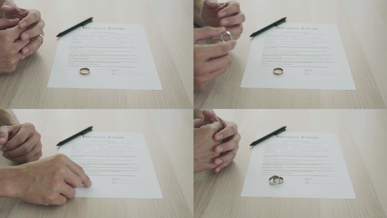 丈夫在等待签署离婚文件之间移除已婚戒指。有家庭问题和离婚或争吵或冲突的恋人的概念