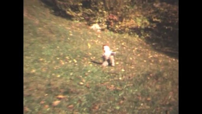 70年代的8毫米镜头-20世纪70年代的小男孩在草地上奔跑，掉在草地上
