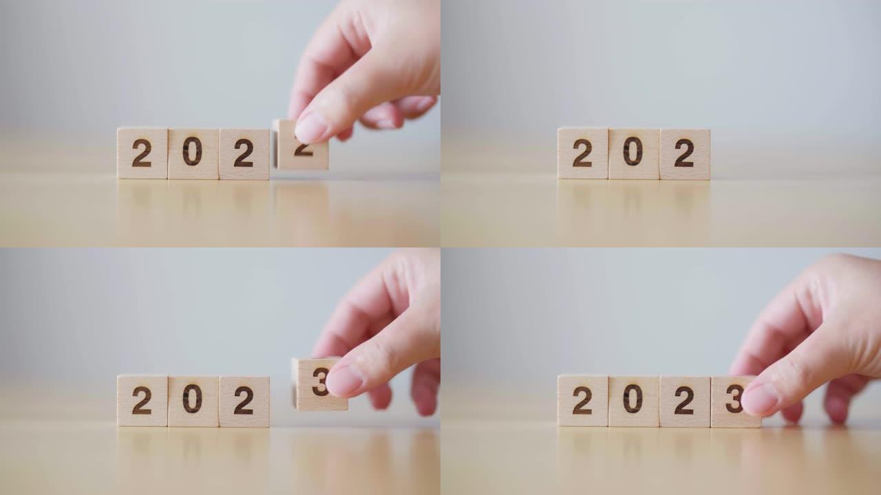 新的2022年变化2023年。用手把木方块和年号。新年决议，圣诞快乐