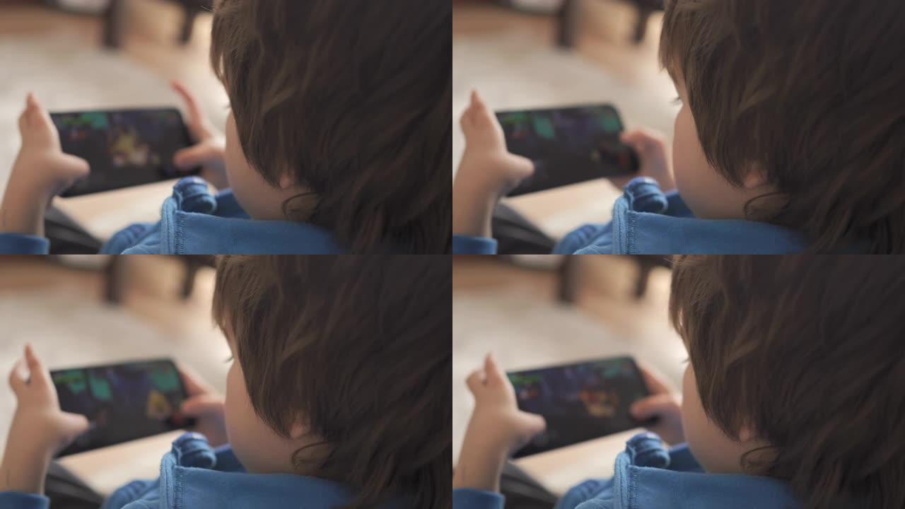 孩子坐在沙发上在家打电话玩游戏。男孩在手机上玩电子游戏。学龄前儿童在沙发上玩电子游戏智能手机。儿童使