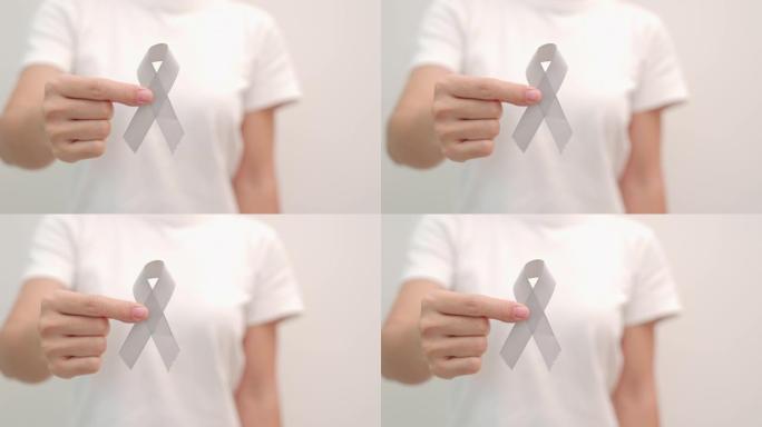 脑癌宣传月，女人手握灰色丝带支持人们生活。医疗保健和世界癌症日概念