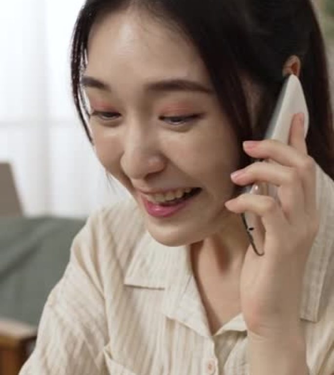 垂直屏幕: 亚洲华人女经理在接到通知电话时兴奋地大喊，说要在客厅在家工作时获得巨大的商机