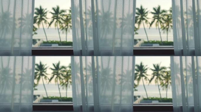 热带海滩的景色。透过玻璃窗观看的观点。美丽的日落，有平静和放松的感觉。背景为海滩和椰子树。泳池别墅在