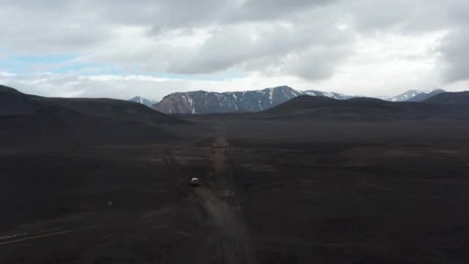 斯卡夫塔费尔国家公园Lakagigar黑色火山沙漠的鸟瞰图，汽车搅动着尘埃云驶出道路。无人机视图4x