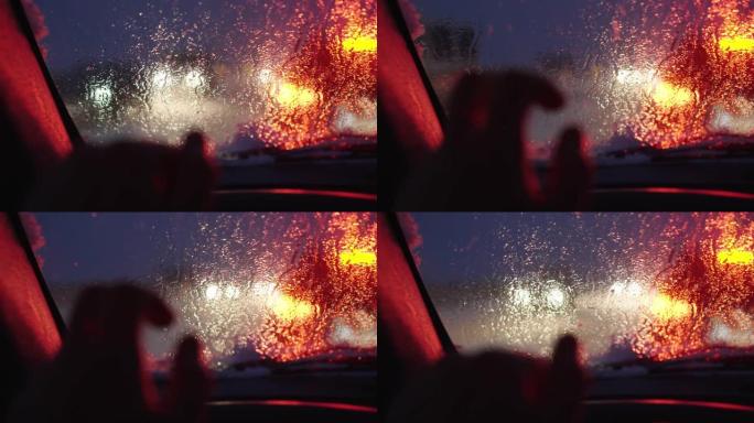 冬季大雪中，夜间道路背景和过往汽车眩光的驾驶员手在方向盘上