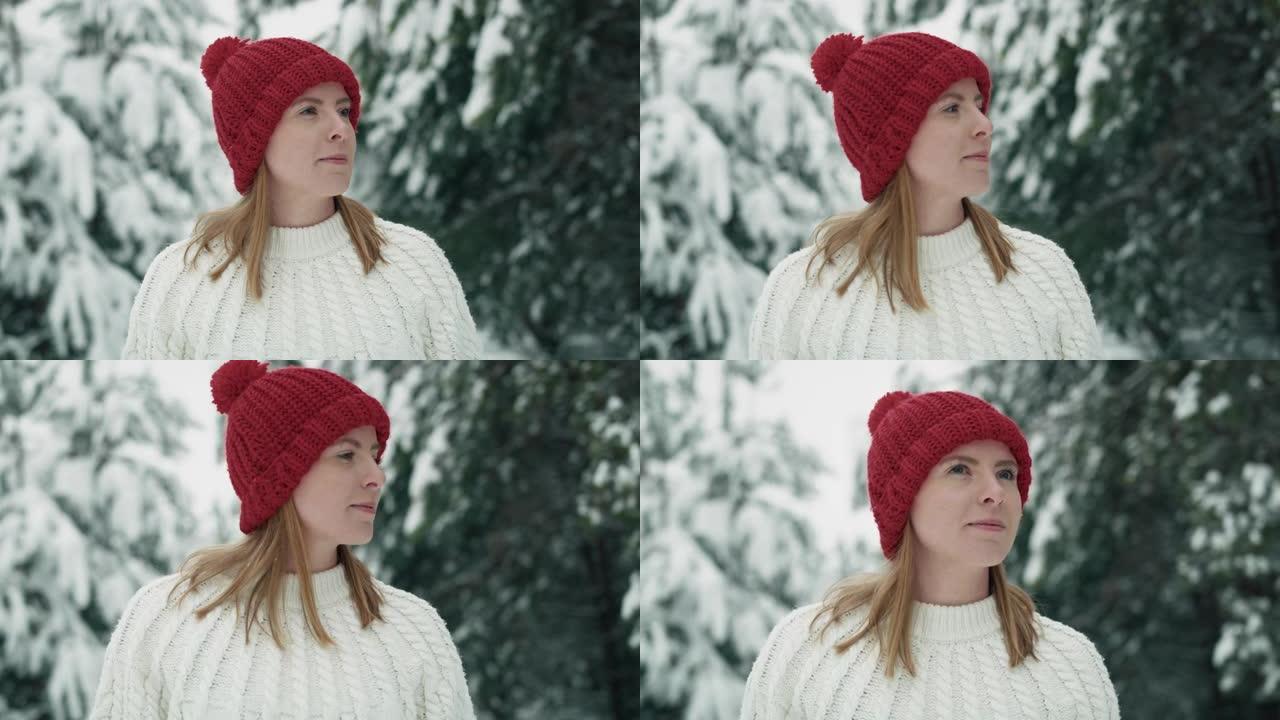 戴着红帽子的白人妇女走在下雪的森林里。用8k的红氦相机拍摄。