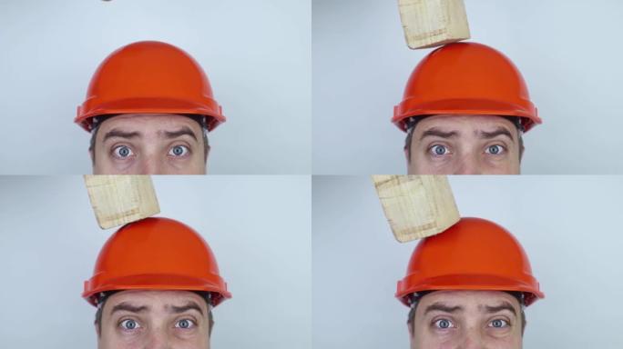安全帽。砖块和一块木板落在建筑商头上。因戴保护性建筑头盔而挽救生命。保护工人免受事故的影响。从高处坠