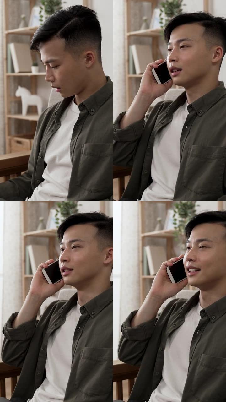 垂直视频: 开朗的亚洲男性创业公司老板在电脑上在家工作时，会接到客户的重要业务电话，并会用手势交谈。