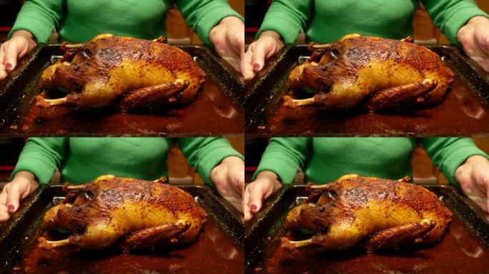 新鲜出炉的鸭子，苹果配有外壳和香料，放在一个女人手中的烤盘上