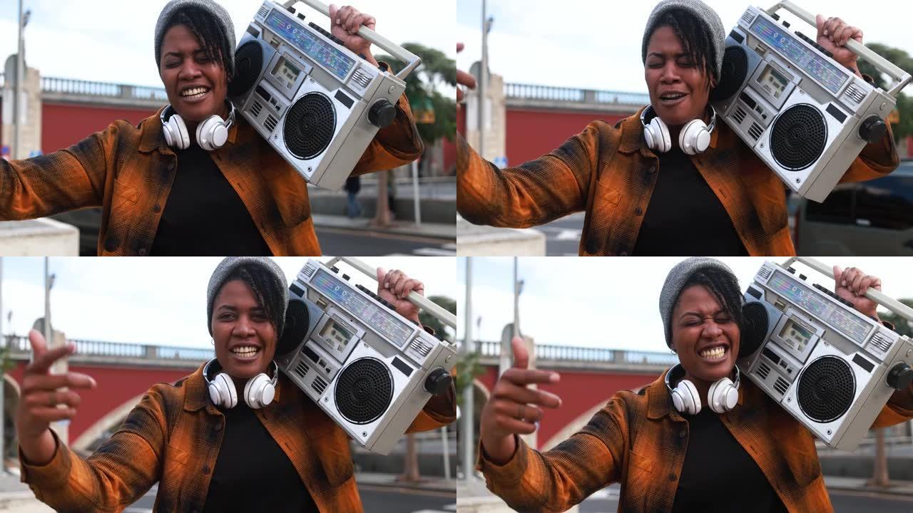 非裔美国妇女说唱一首拿着老式音箱立体声音响的歌曲，背景是城市街道 -- 地下生活方式概念