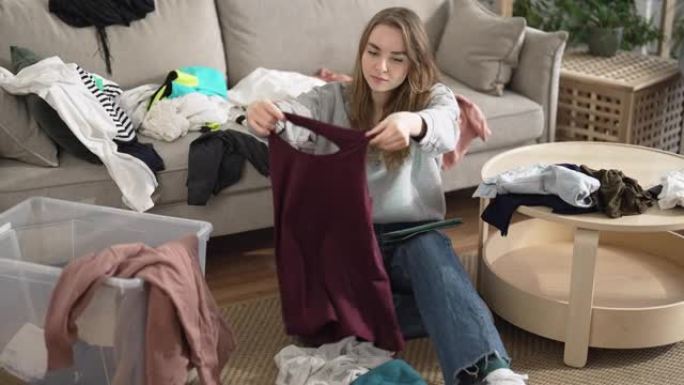 一名年轻女子在捐款箱中折叠并整理衣服