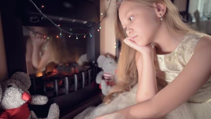 一个穿着节日礼服的小女孩，在节日的灯光和圣诞树的背景下，悲伤地看着模糊和运动的某个地方聚焦。被宠坏的