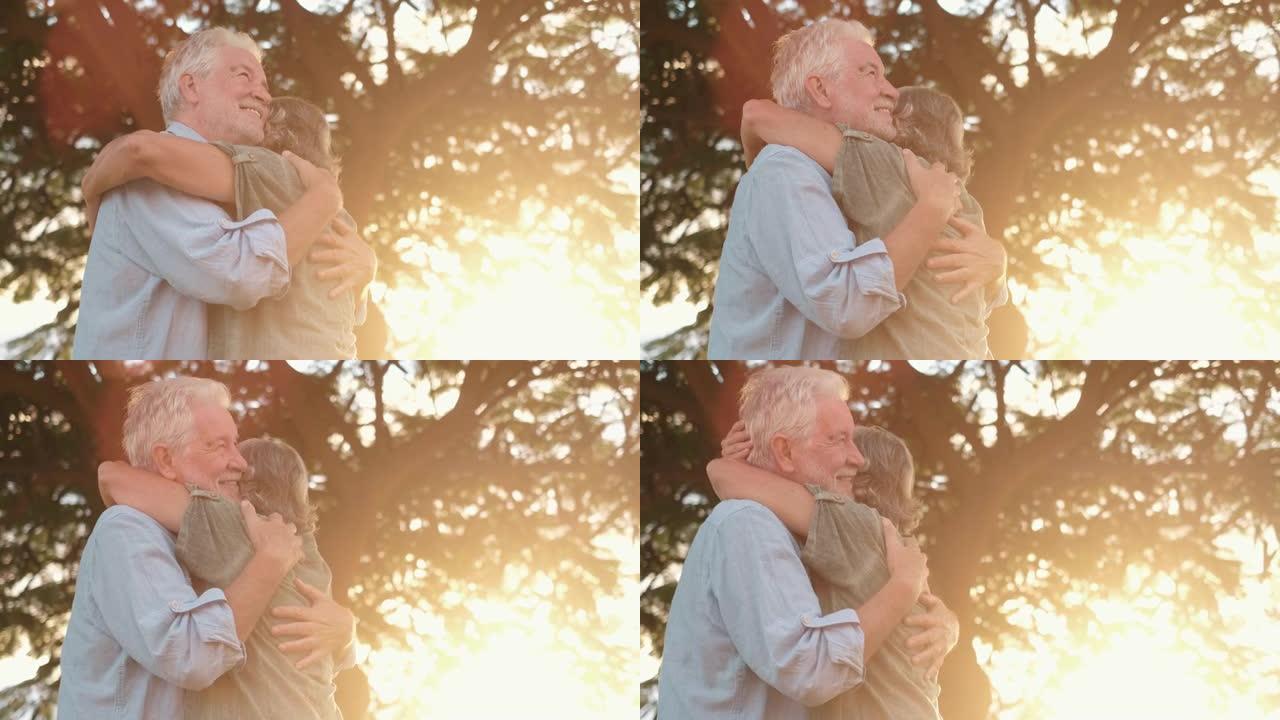 头像特写肖像快乐的白发中年妇女依偎在微笑的老丈夫身边，在公园享受温柔的时刻。相爱的老家庭夫妇拥抱，感