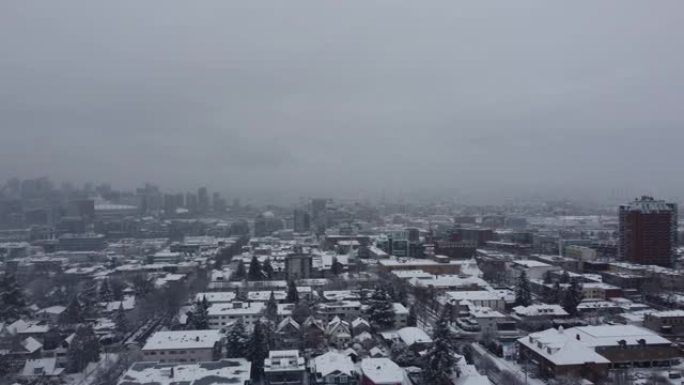 在冬季阴天，飞越白雪皑皑的屋顶和温哥华市中心