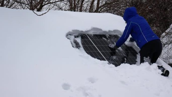 一个女孩从房子屋顶上的雪地上清洗太阳能电池板。需要清洁太阳能电池板。