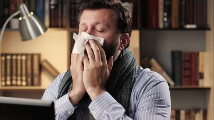 咳嗽。在办公室或公寓工作场所感冒的人在笔记本电脑上工作，开始剧烈咳嗽。感冒流感治疗理念