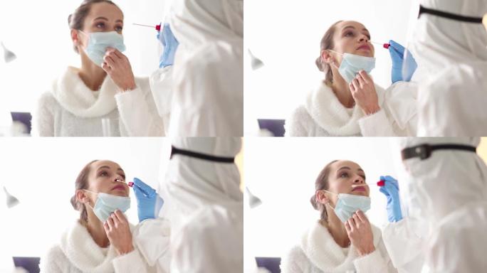 身穿防护服的医生从一名妇女的鼻子上取棉签