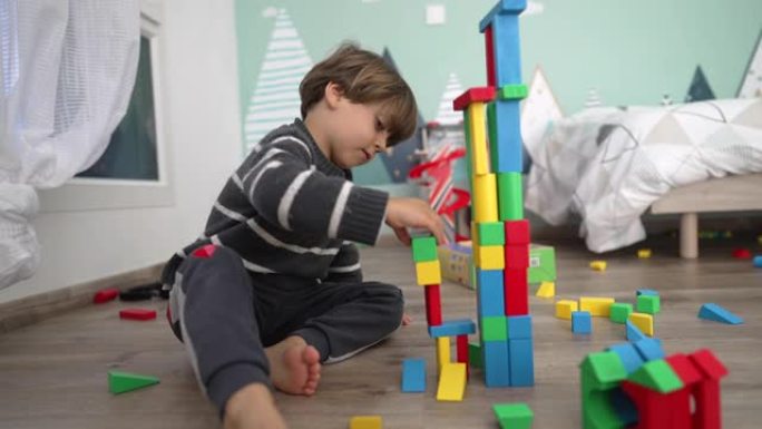 孩子在地板上玩积木。孩子意外摧毁塔的生活方式镜头。一个在卧室玩耍的小男孩