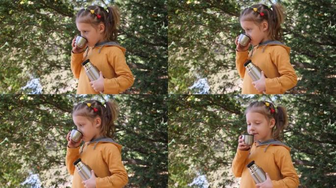 公园里的儿童小可爱女孩从保温杯里喝茶