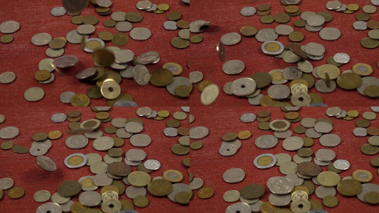 各种硬币落在一堆硬币旁边的红色表面上，慢动作