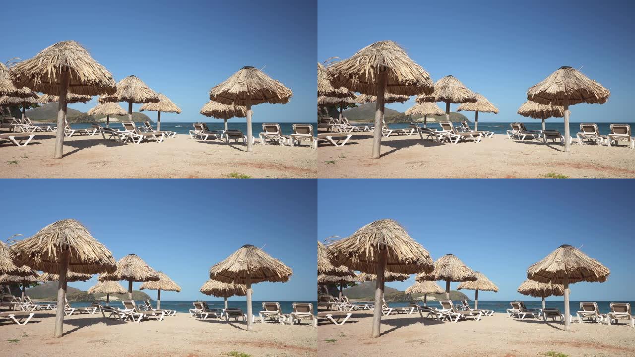 一大早在无人的海滩上撑着草伞和日光浴椅。在美丽的海滨度假