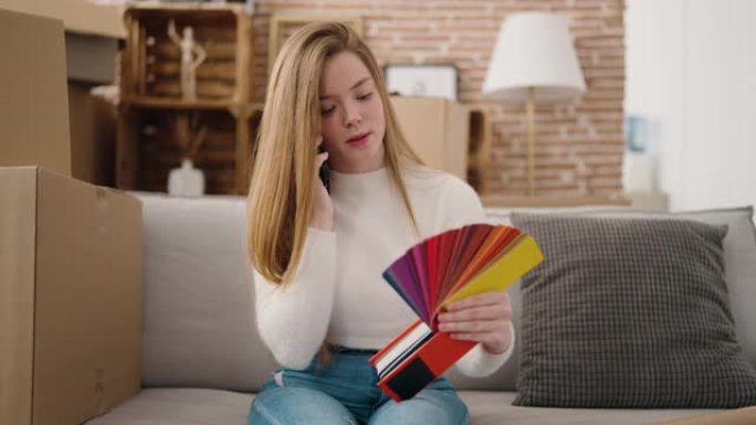 年轻的金发女人在智能手机上聊天，选择新家的油漆颜色墙