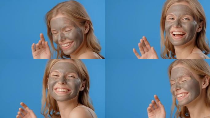 快乐的女人在应用粘土面罩中微笑。女性化妆品用法。蓝色屏幕上的美容护理，4k Prores总部