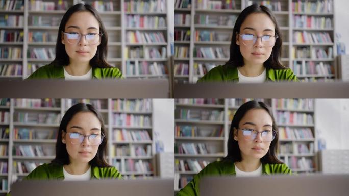 亚洲学生戴眼镜坐在图书馆网上学习