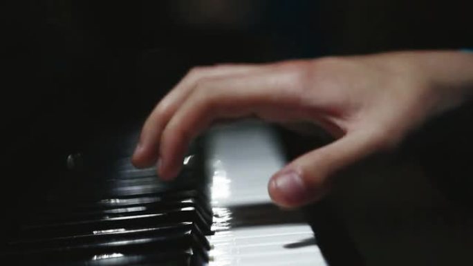 钢琴键以深色关闭。学生训练弹钢琴。男人两只手在教室里用漂亮的三角钢琴演奏柔和的古典音乐。