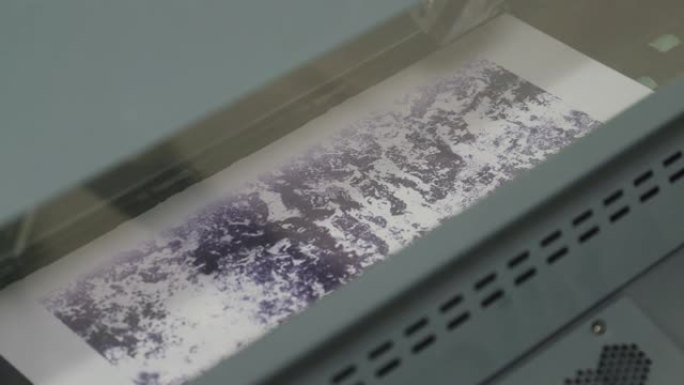 打印紫色图案的工业打印机的特写镜头。打印头来回移动。
