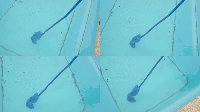男子用便携式真空吸尘器打扫游泳池。为游泳区准备和清洁游泳池