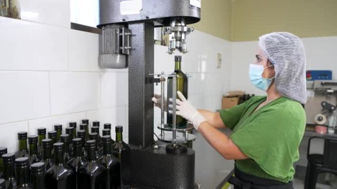 在小型橄榄油企业包装工作的拉丁妇女用工业机械密封盖子