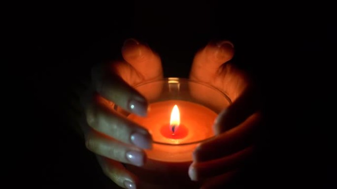 女人在黑暗的夜晚在家中点燃蜡烛的特写镜头