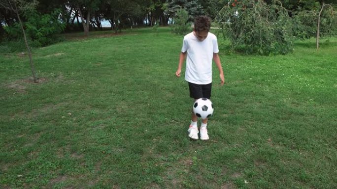 十几岁的男孩在户外踢足球，夏天在公园踢球。