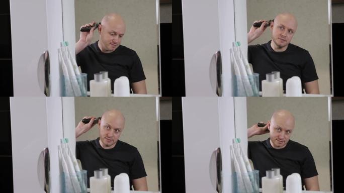 一个秃头男人在浴室里用电动剃须刀剃光头。