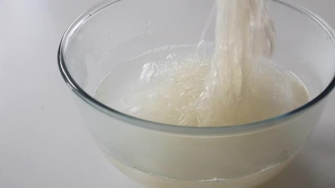 用筷子在热水中搅拌和冲洗玻璃纸面条 (funchose，fansi)