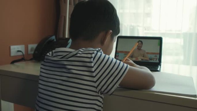 亚洲男孩正在在家参加在线课程。