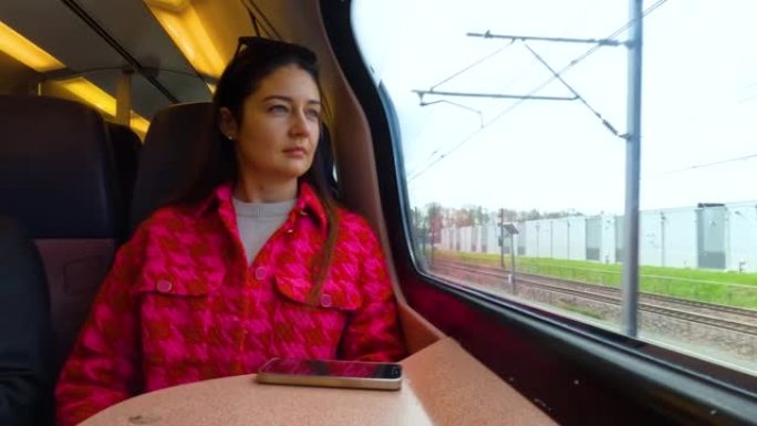 白人女性坐在行驶中的火车上，从窗户向外看