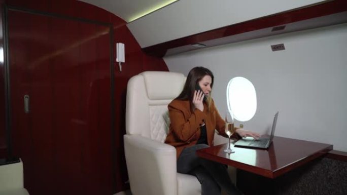 乘坐飞机的年轻女子，乘坐私人飞机或头等舱的女孩。带笔记本电脑和香槟豪华旅行的女商人