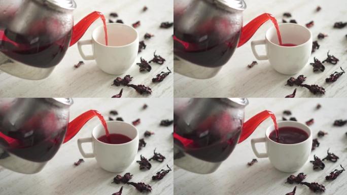 红色饮料是从玻璃茶壶中倒出的。新鲜煮茶配覆盆子，茶配荚果
