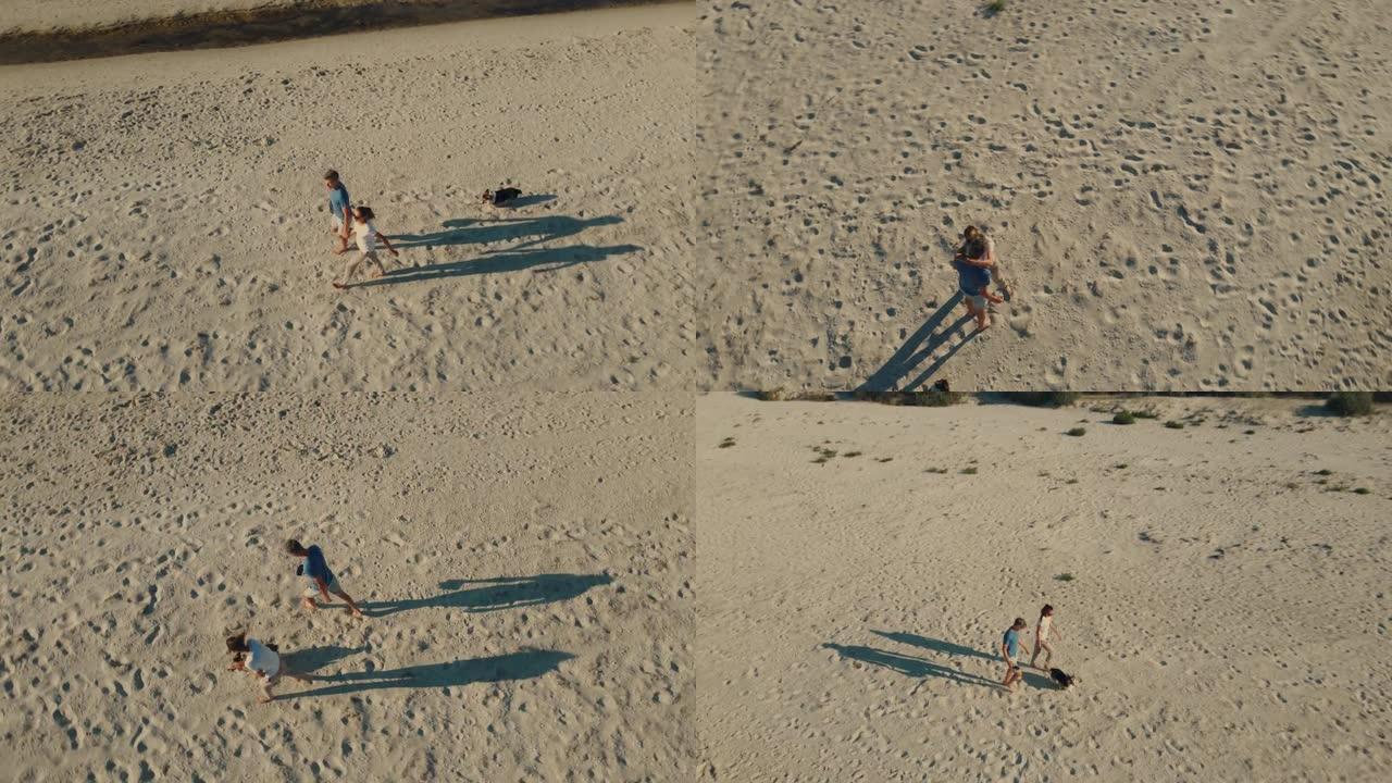 快乐无忧无虑的夫妇与狗威尔士柯基 (welsh corgi) 的无人机的航拍镜头沿着荒岛岸边的沙滩漫