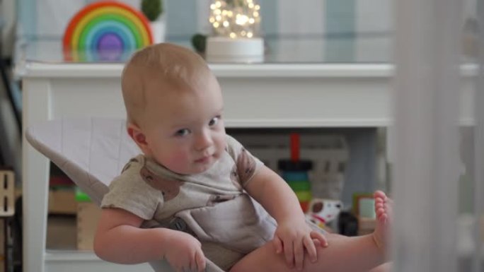 可爱的婴儿坐在婴儿保镖里，10个月大的高加索孩子用腿和手臂肌肉上下弹动。